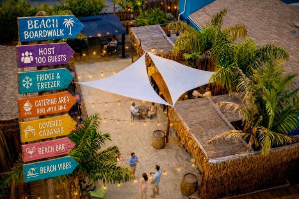Resort beach boardwalk with sail shades, cabanas, and string lights